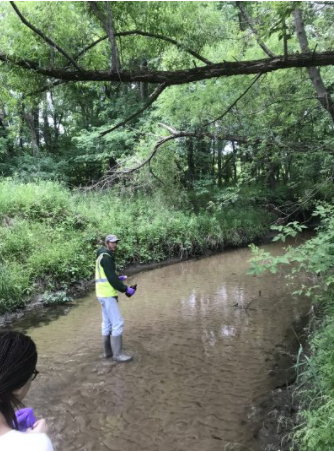 Greg looks over his shoulder as he stands in a creek