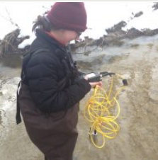 A person holds a technical instrument with a long, yellow tube attached 