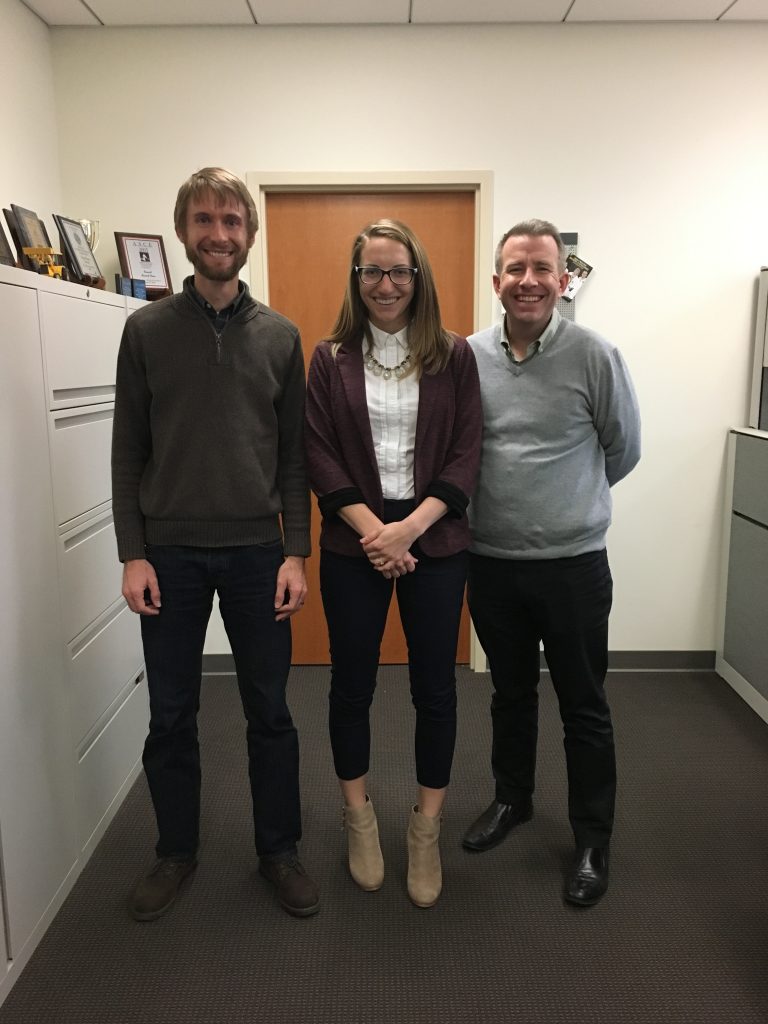 Greg LeFevre stands with two other people in an office.